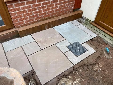 Large format paving tiles arranged on ground during outdoor hardscaping installation project