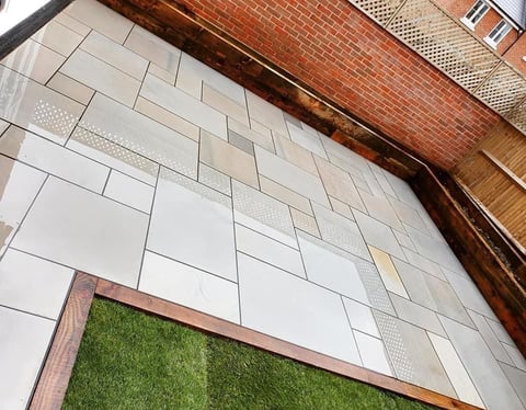 White subway tile wall with wood trim and a green grass doormat at the entrance